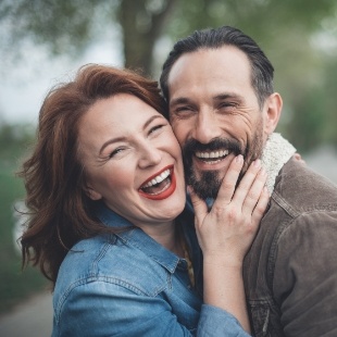 Man and woman smiling outdoors after visiting dental office in Nepean