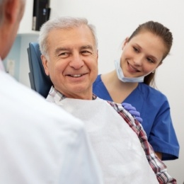 Senior dental patient smiling at his dentist