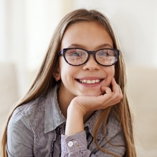 Young girl with glasses smiling after visiting childrens dentist in Nepean