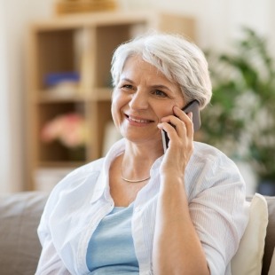 Senior woman using her phone to contact dental office in Nepean