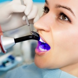 Woman receiving cosmetic dental bonding on her upper front tooth