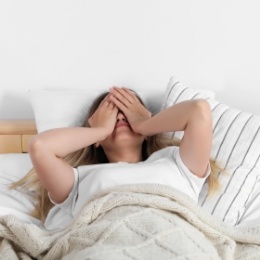 Woman laying in bed and rubbing her eyes