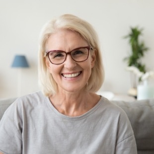 Senior woman on couch smiling with dentures in Nepean