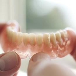 Hands holding a full denture