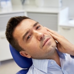 Man holding his cheek in pain while visiting emergency dentist