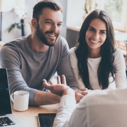 Man and woman smiling at person sitting across desk