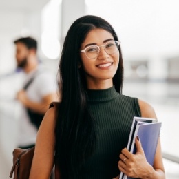 Smiling woman wearing glasses and holding books