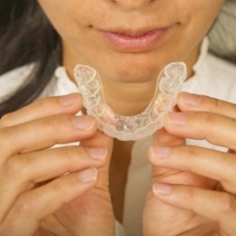 Woman holding an Invisalign aligner near her mouth