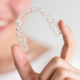 Hand holding an Invisalign clear aligner