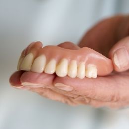 Hand holding a full upper denture