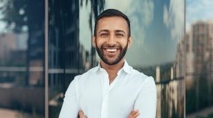 Man in white collared shirt smiling with his arms crossed