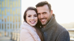 Man and woman smiling outdoors in winter coats