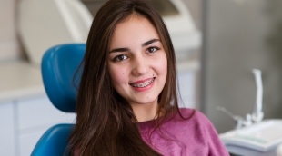 Teenage girl with braces sitting in dental chair