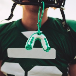 American football player with an athletic mouthguard hanging from their helmet