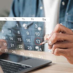 Person circling date of dental appointment on holographic calendar