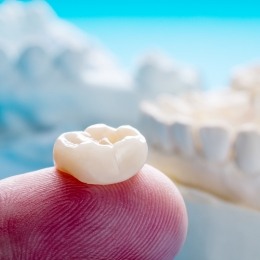 Close up of a dental crown resting on a finger