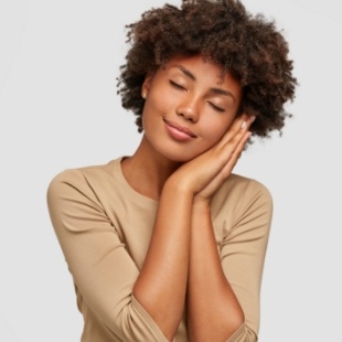 Woman making a pillow shape with her hands and miming sleeping