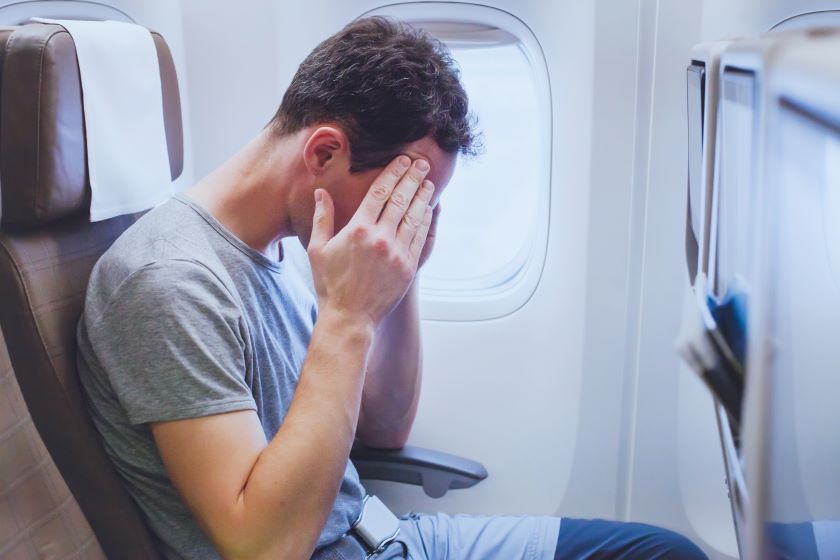 A man in pain riding on a plane.